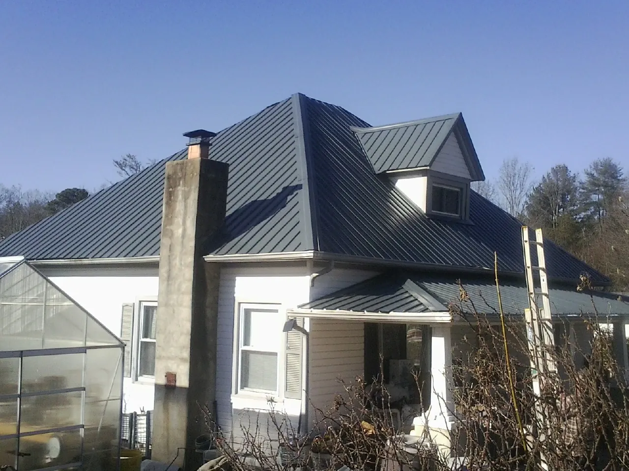 Dark blue standing seam metal roof on a white farmhouse with dormer — Slate & Tile Roof Repair by Roofing Brothers in Selma