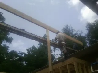 Carpenter setting a ridge beam over a new addition frame — Ice Dam Removal by Roofing Brothers in Selma