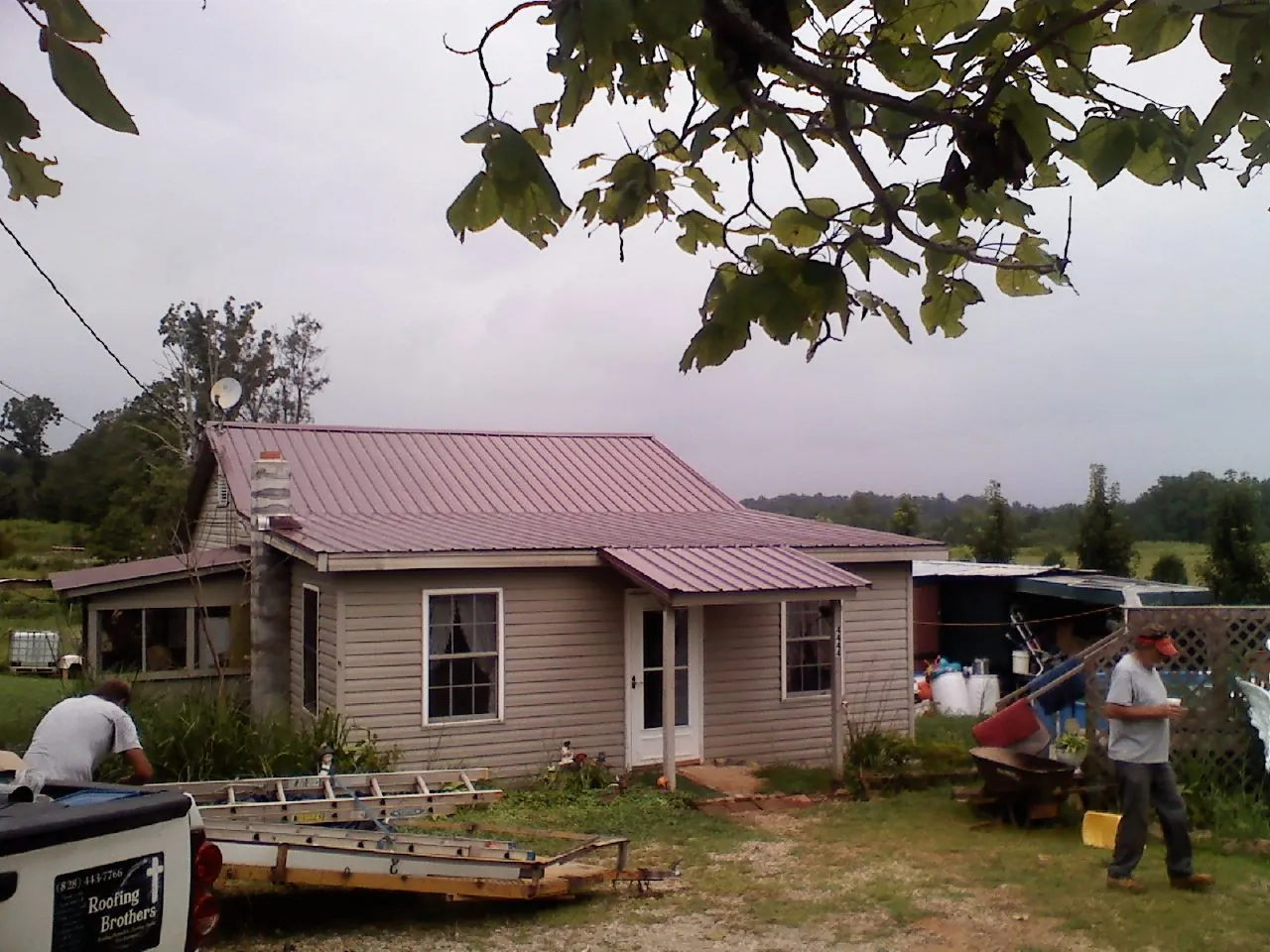 Crew finishing a mauve metal roof on a small farmhouse in Selma
